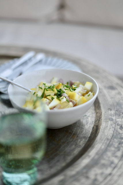 Kartoffelsalat mit Schnittlauch in einer weißen Schale